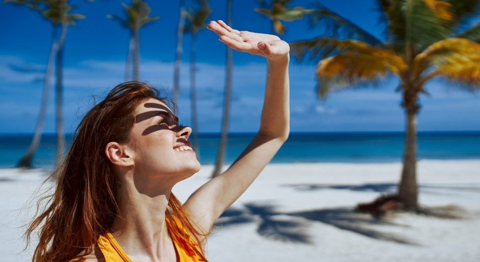 تصویر زنی با لباس زرد در ساحل رو به نور خورشید- درمان خانگی لک های پوستی